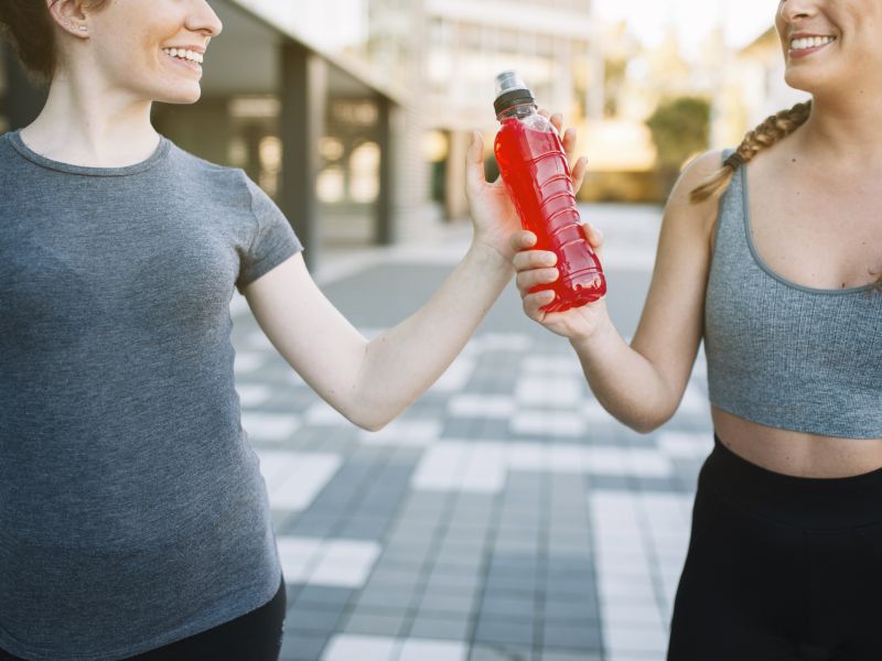 Cosecha mujeres en forma alegre con bebida roja