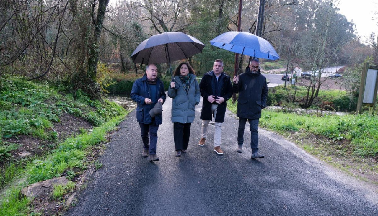 El alcalde de Rois, Ramón Tojo Lens, pasea bajo la lluvia acompañado de la delegada de la Xunta en A Coruña, Belén do Campo, y el regidor de Brión, Pablo Lago
