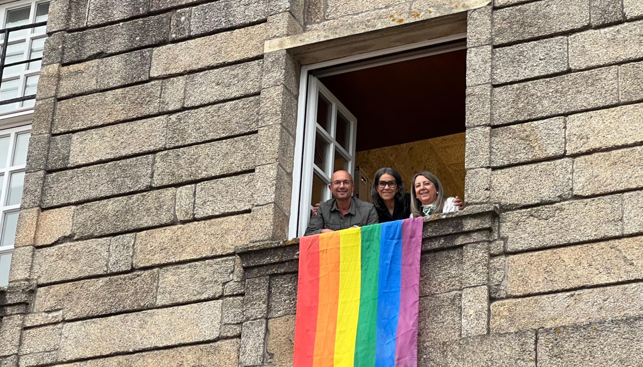 IMG-Mercedes Rosón, Gonzalo Muíños e Mila Castro desde a xanela do despacho das Non Adscritas coa bandeira LGTBIQ+